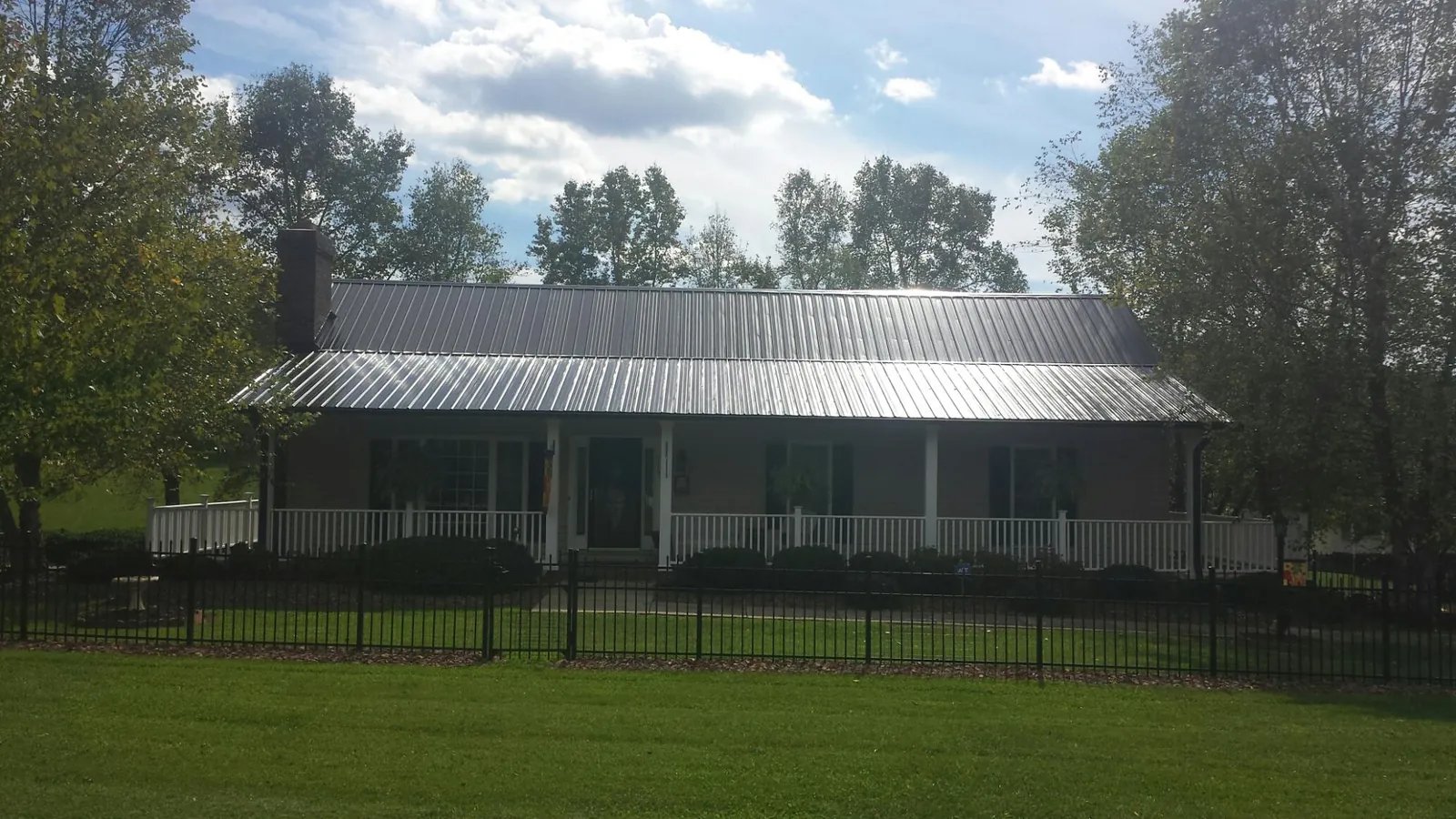 Gray metal roof on a brick ranch with a full width front porch — Gutter Guard Installation work by our crew in Vale
