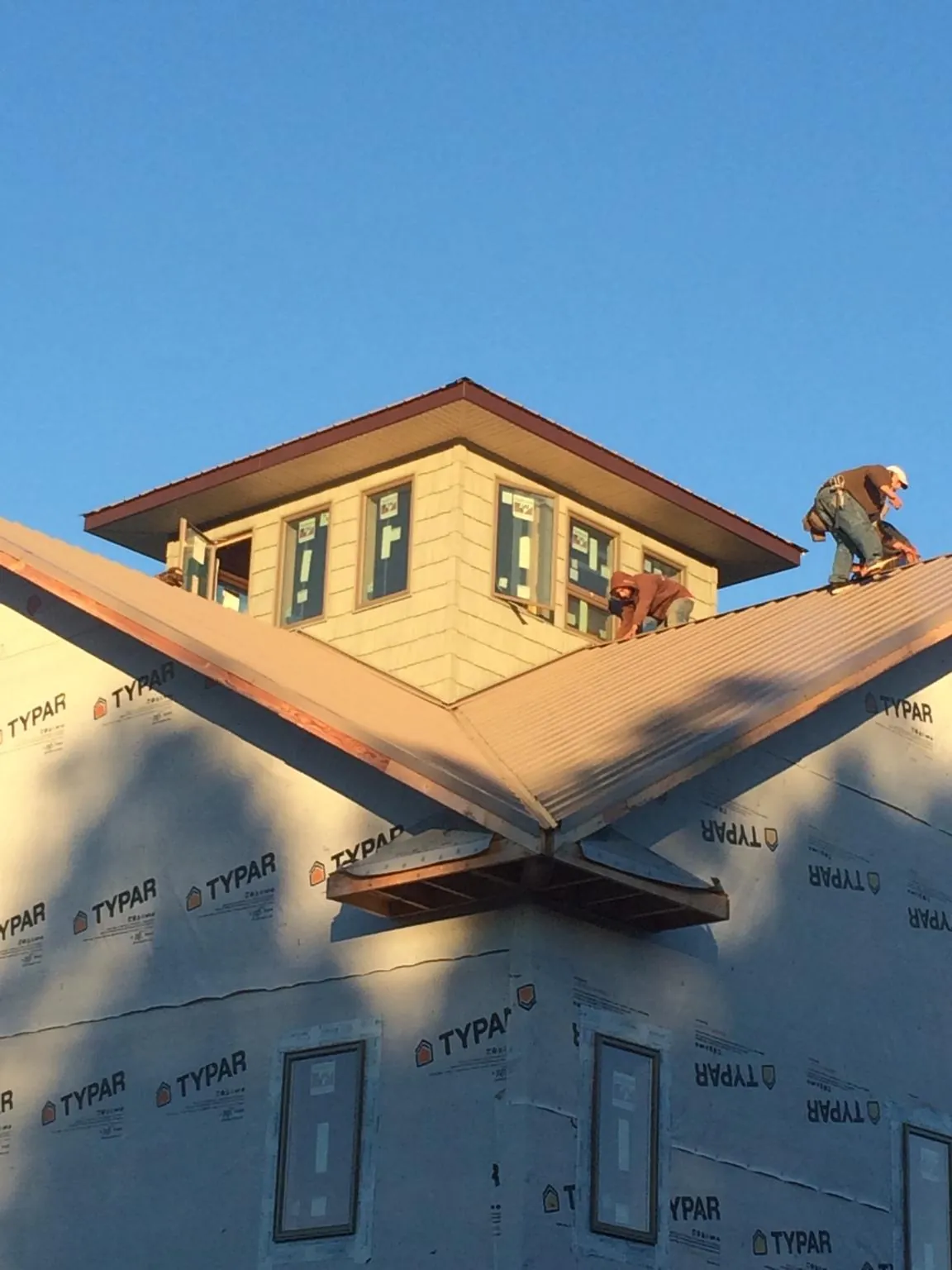 Roofers working around a rooftop cupola on a new metal roof at sunset — Roof Waterproofing in Vale by Roofing Brothers